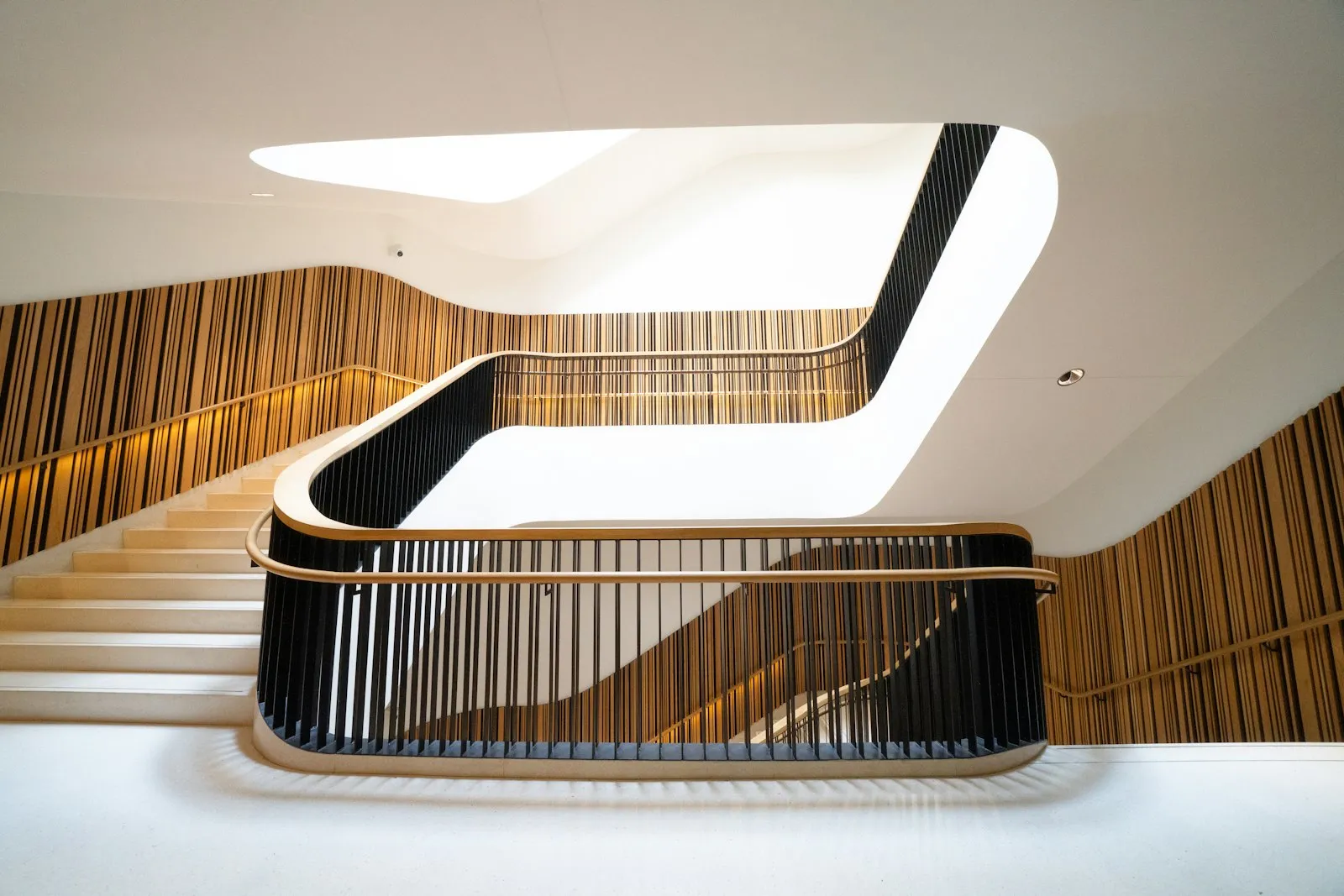 Tangga interior modern dengan anak tangga kayu dan railing hitam, lampu gantung bulat di sepanjang tangga